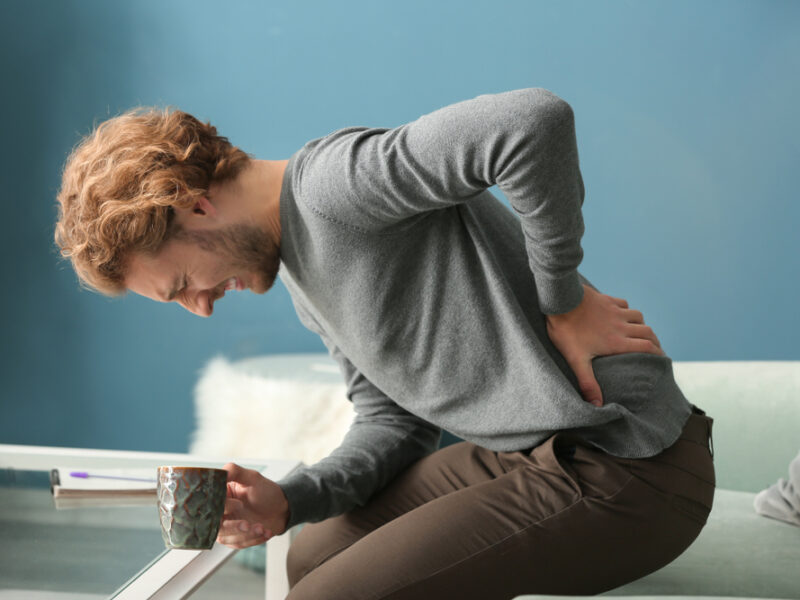 Man with coffee and back pain